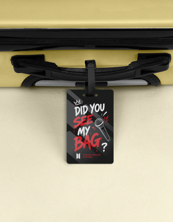 Black luggage tag with red and white graffiti text did you see my bag, crown and microphone design, BTS Mic Drop inspired, attached to a suitcase handle"