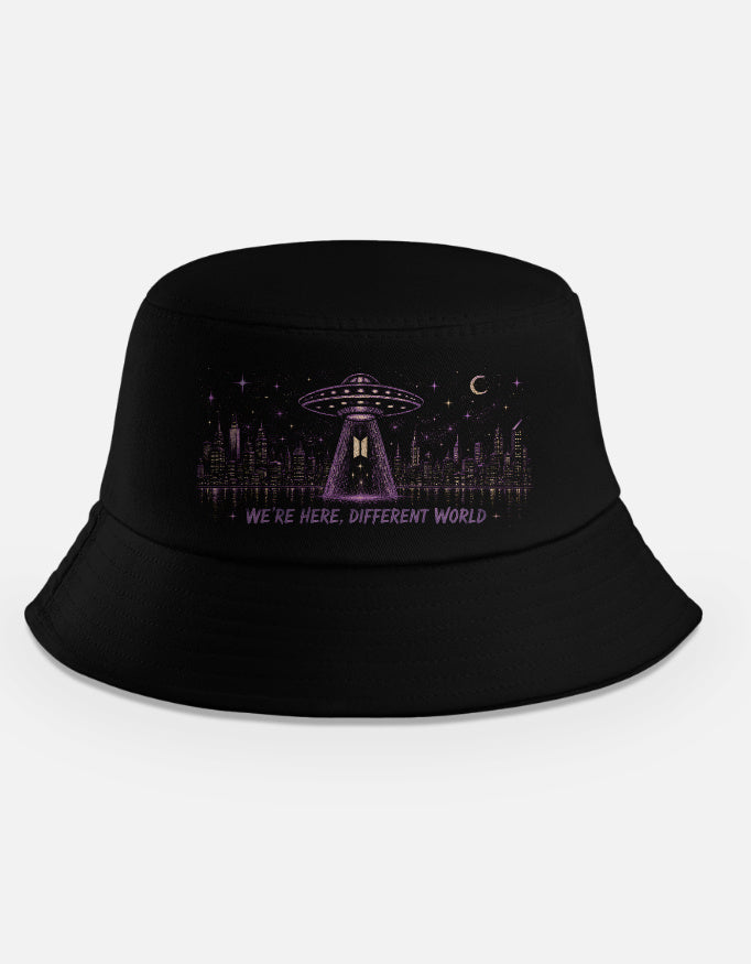 Black bucket hat with purple UFO beaming light over a city skyline at night with text we're here different world, BTS alien theory inspired design"
